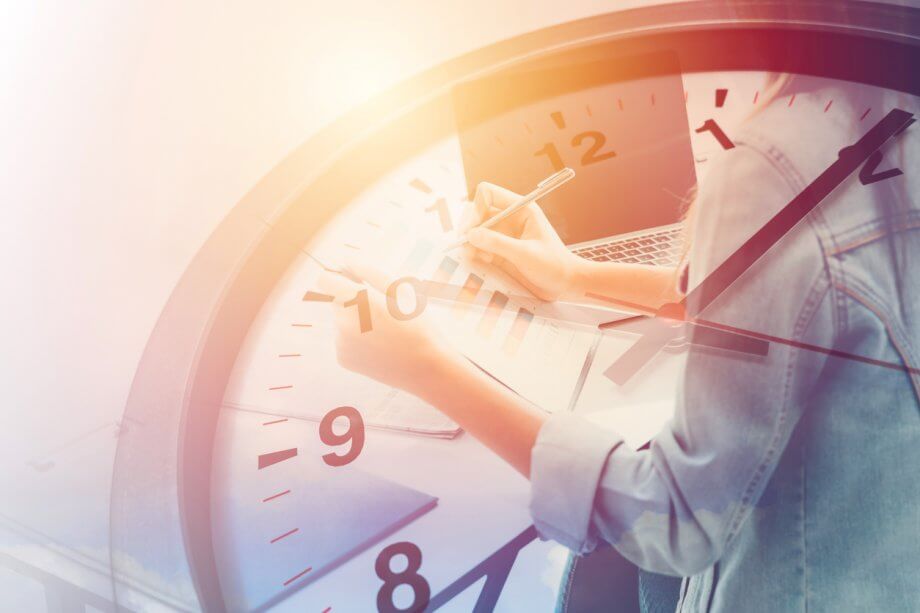 Photograph of a busy person at a desk writing while surrounded by papers with an image overlay of a clock ticking.